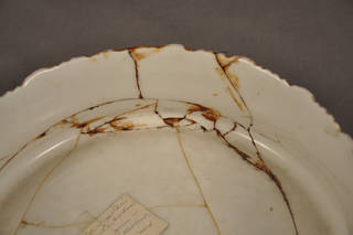 Porcelain plate, example of adhesives from previous repairs becoming discolored