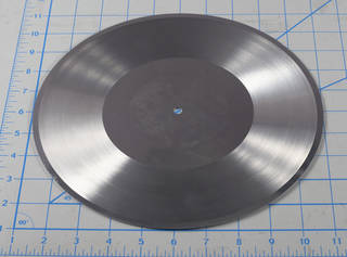 Aluminum disc photographed with ruler for scale